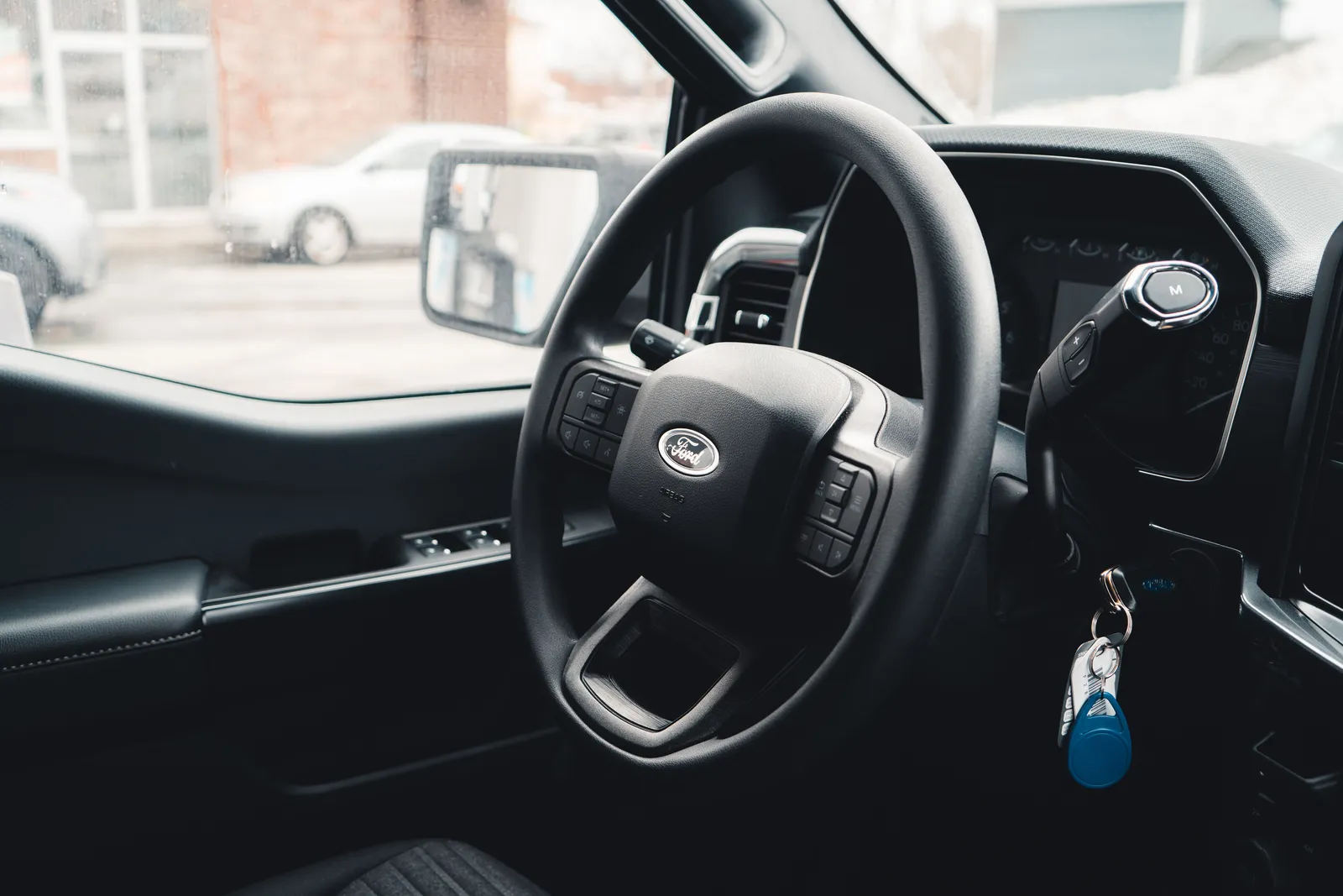 Keys hanging from the ignition beside the steering wheel of a vehicle