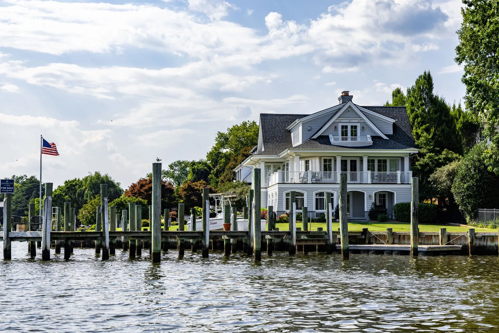 White waterfront house with a wooden dock and moored boats