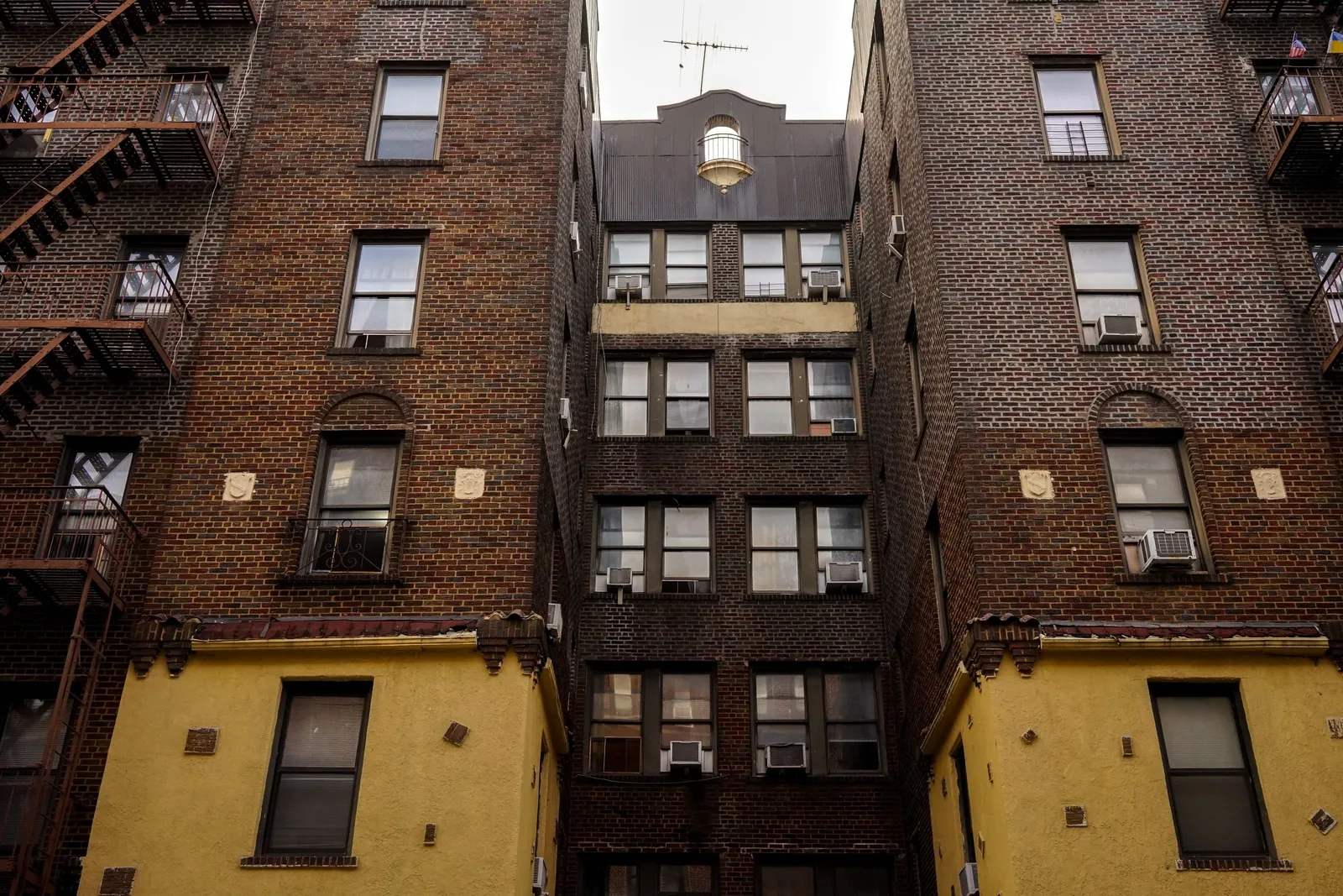 Brick apartment buildings with fire escapes, seen from street level