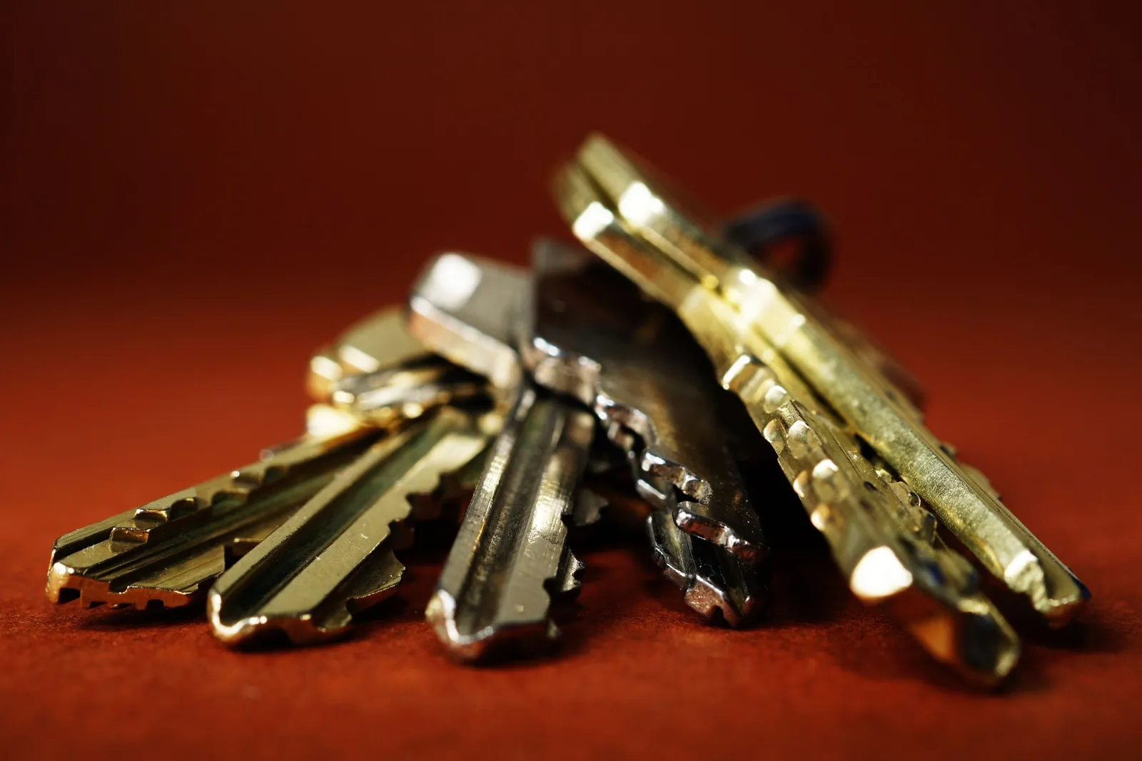 A bunch of brass door keys against a dark red background