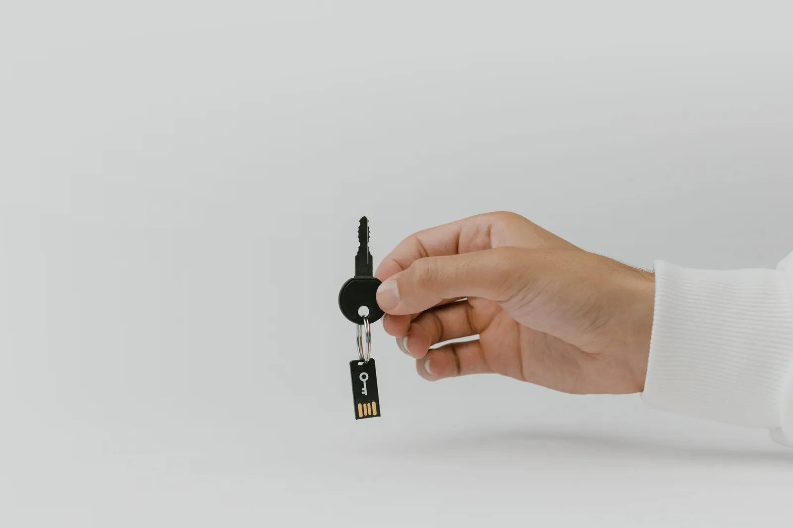 Hand holding out a single key against a white background