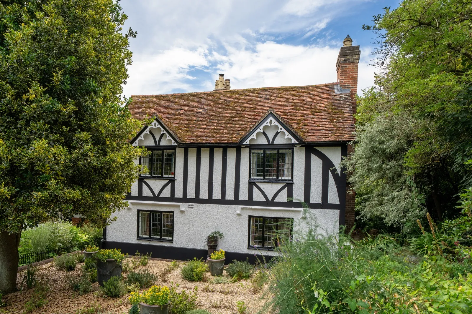 Tudor-style house with timber framing among garden trees