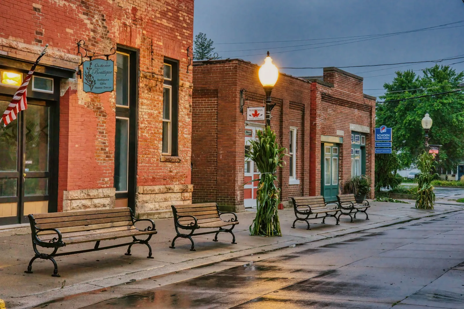 Brick shopfronts with benches and a street lamp on a small-town avenue