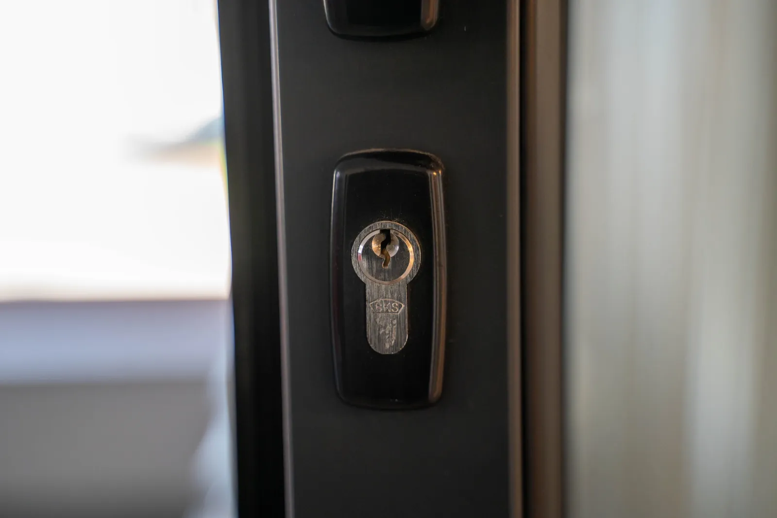 Lock cylinder set in a dark aluminium commercial door frame