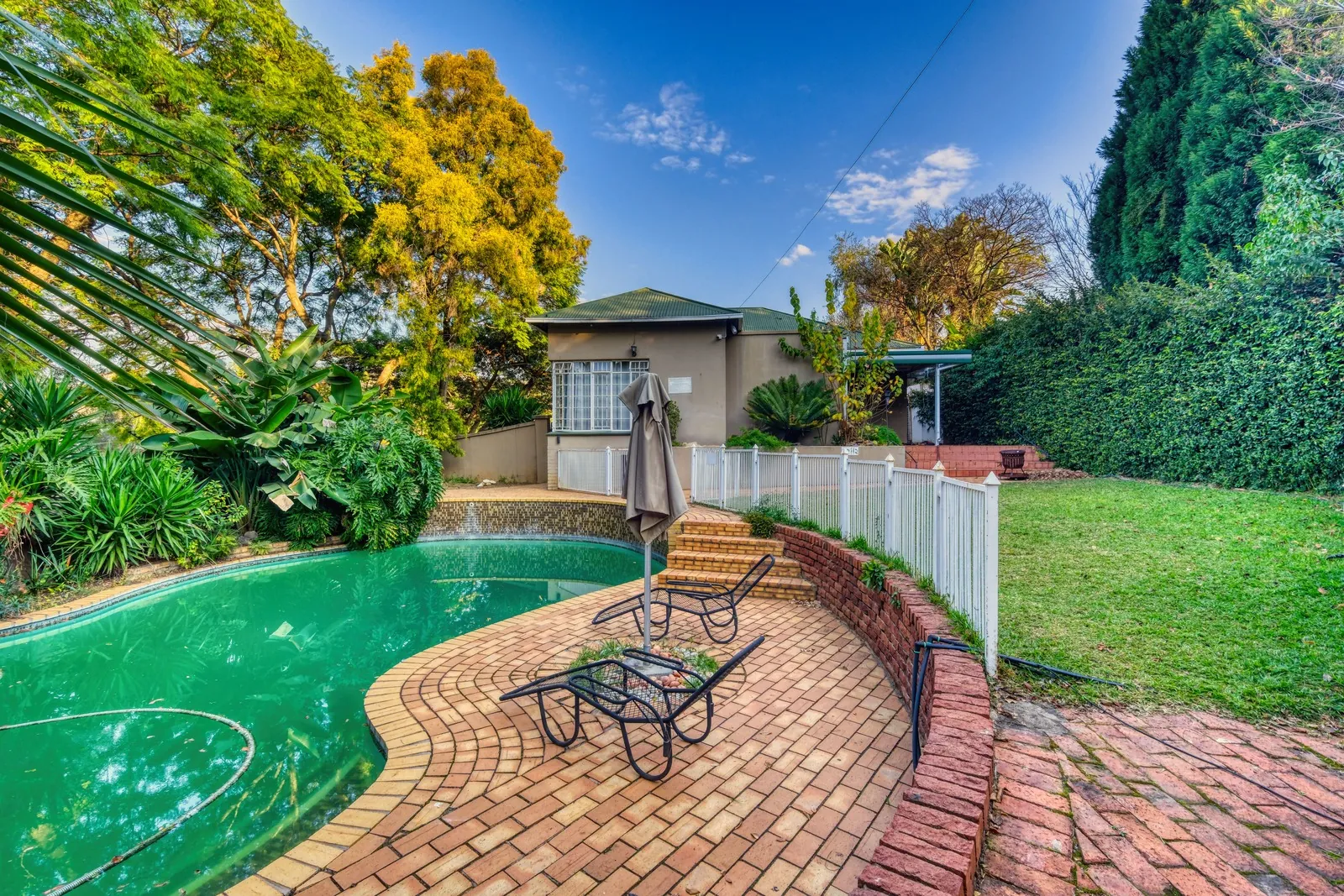 Backyard swimming pool beside a white picket fence