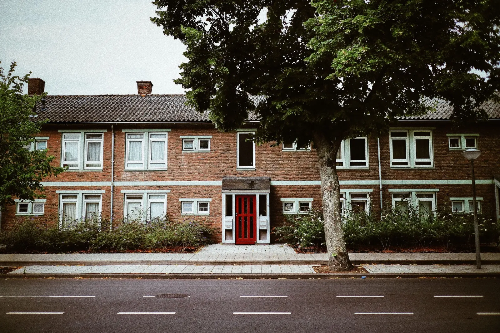 Low brick apartment building with a red front door on a quiet street