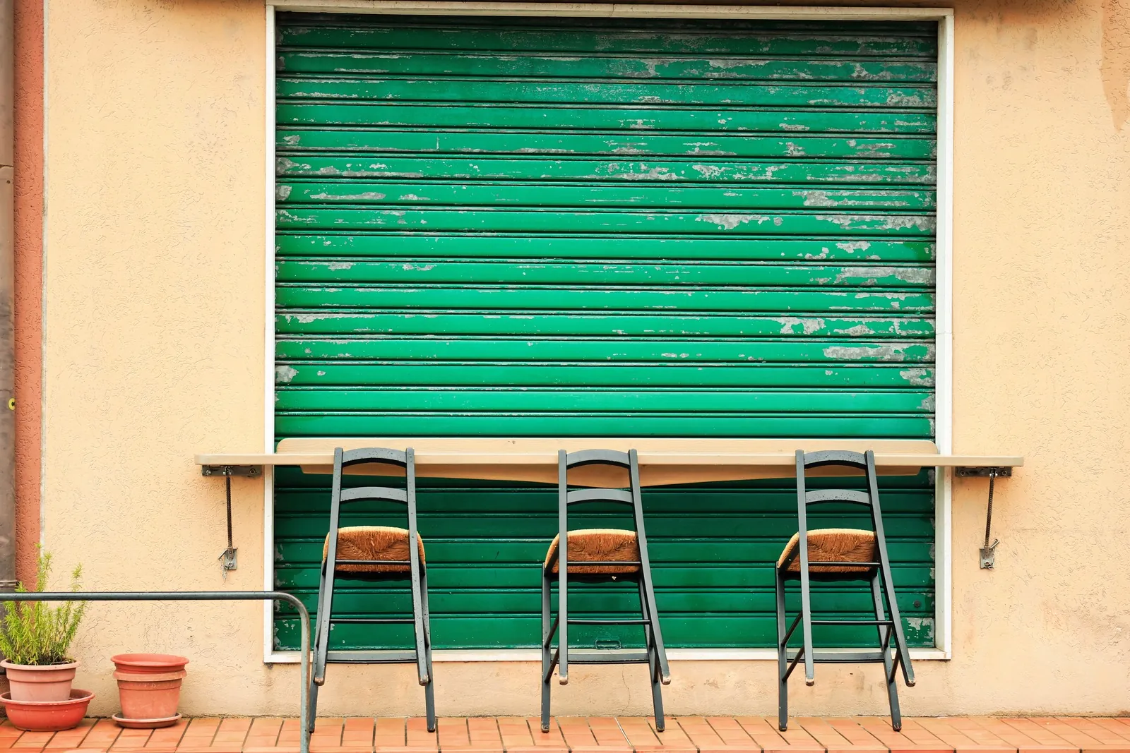 Green roll-down security shutter over a shop window