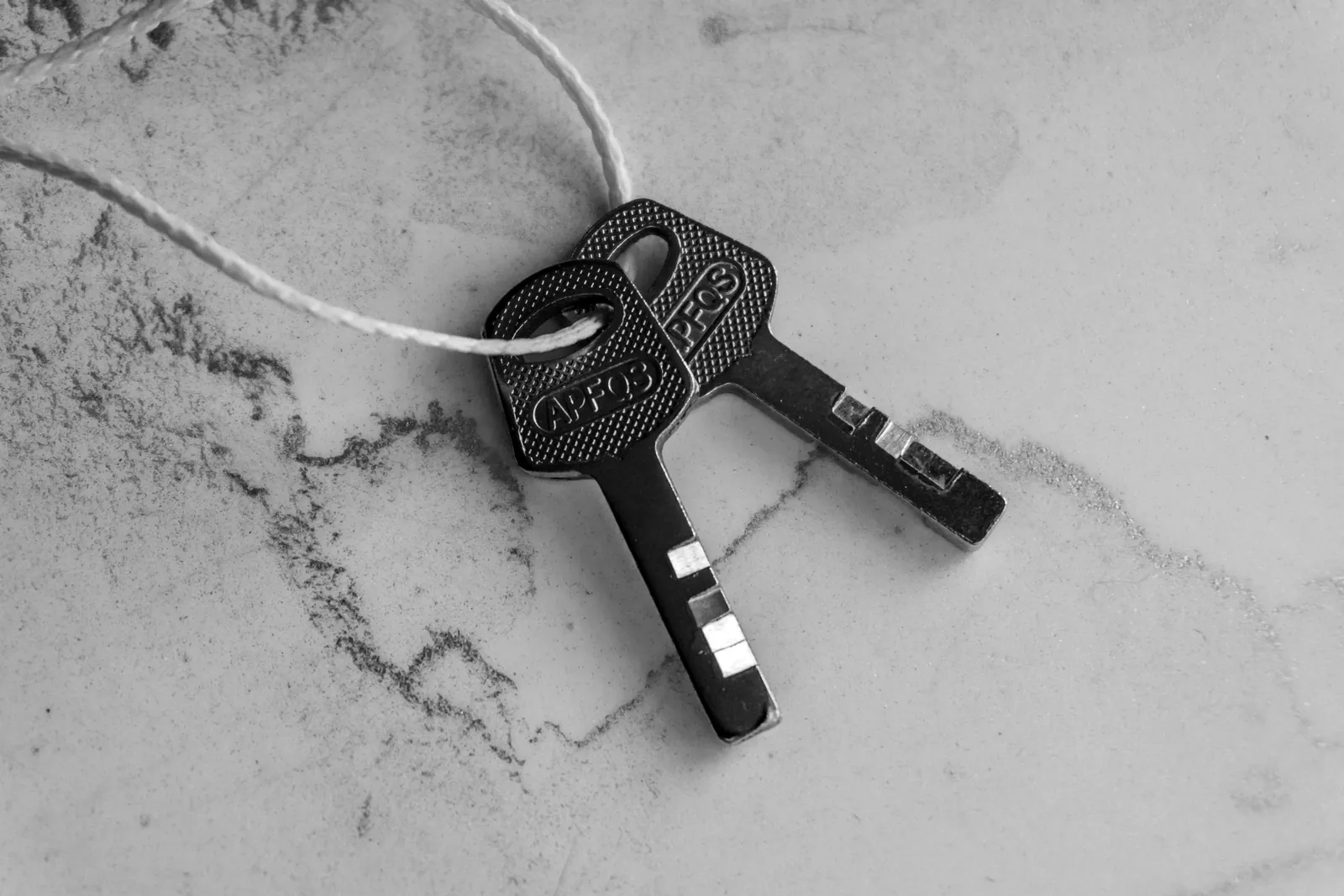 Two keys on a string on a grey marble surface