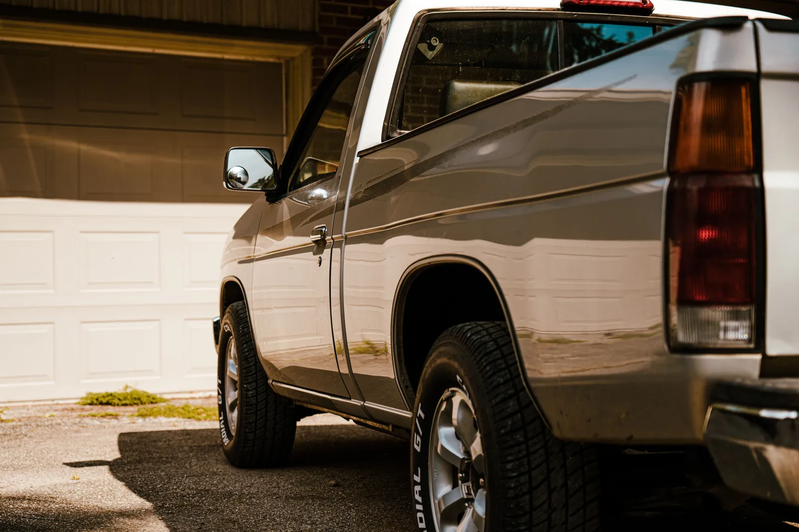 A silver pickup truck parked in a driveway in front of a garage door