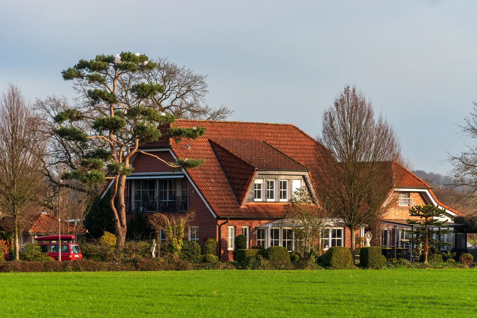 Large brick house with a tiled roof behind a wide lawn